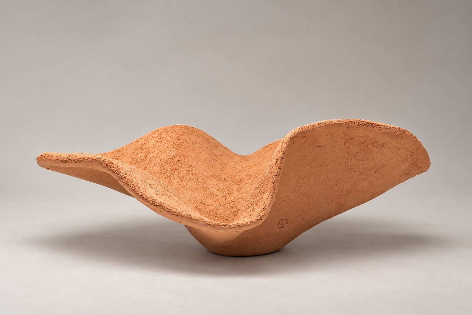 Cuenco escultórico de terracota con bordes ondulados y textura artesanal