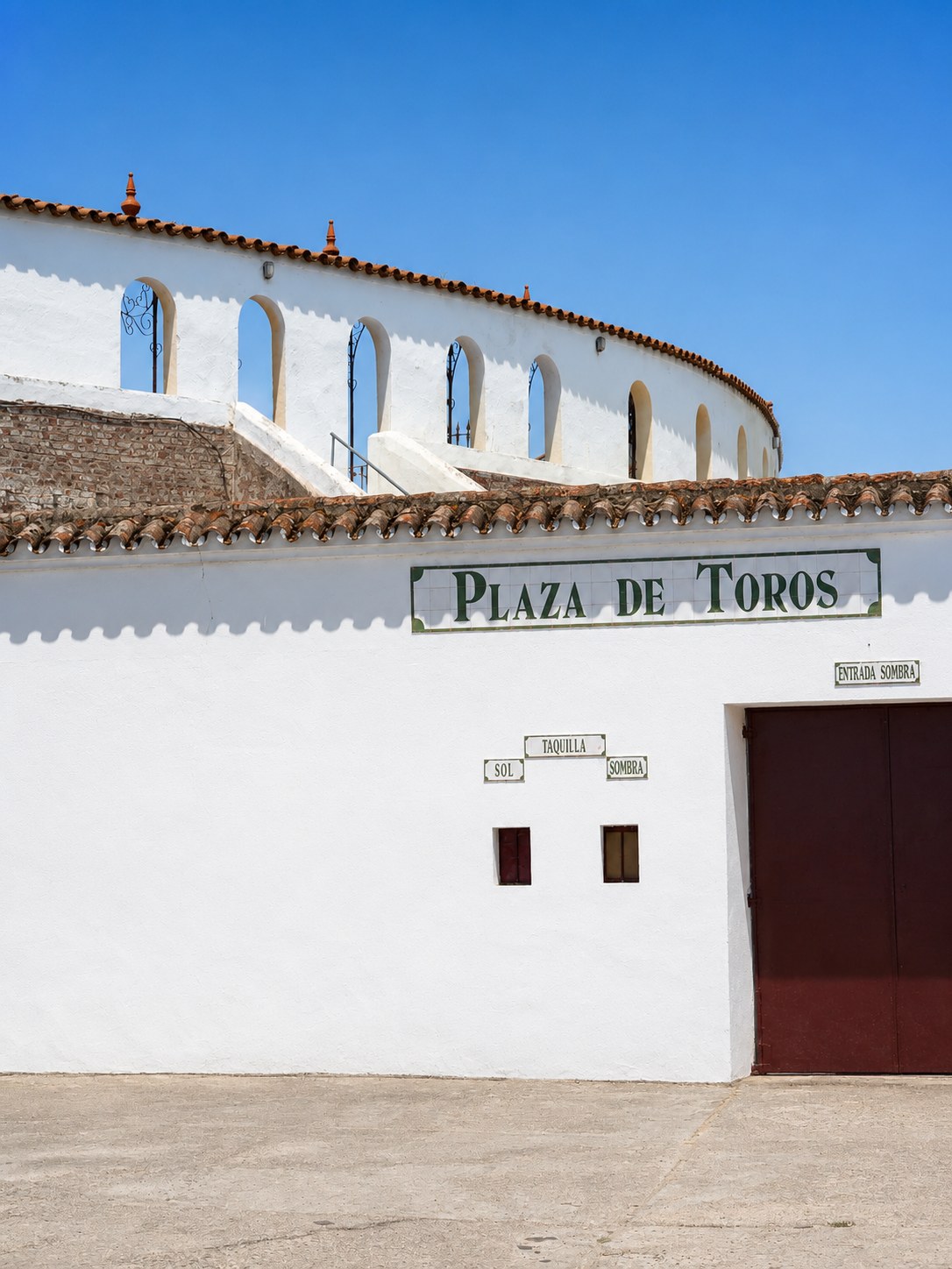 Fachada blanca de la plaza de toros bajo un cielo azul
